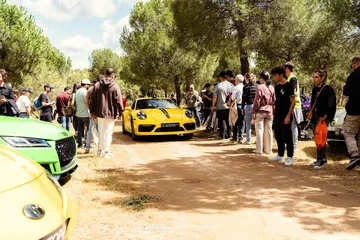 Porsche amarillo captado en evento automovilístico rodeado de aficionados