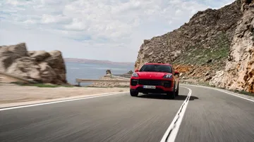 Vista dinámica del Porsche Cayenne GTS 2024 abordando una curva con elegancia.