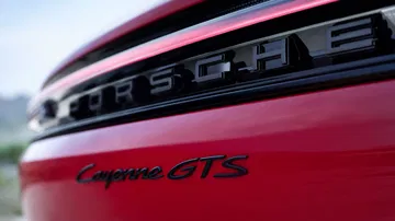 Vista cercana del emblema y nombre modelo Porsche Cayenne GTS en rojo.