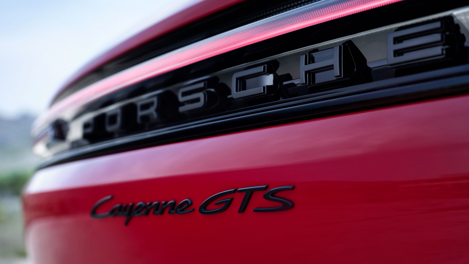 Vista cercana del emblema y nombre modelo Porsche Cayenne GTS en rojo.