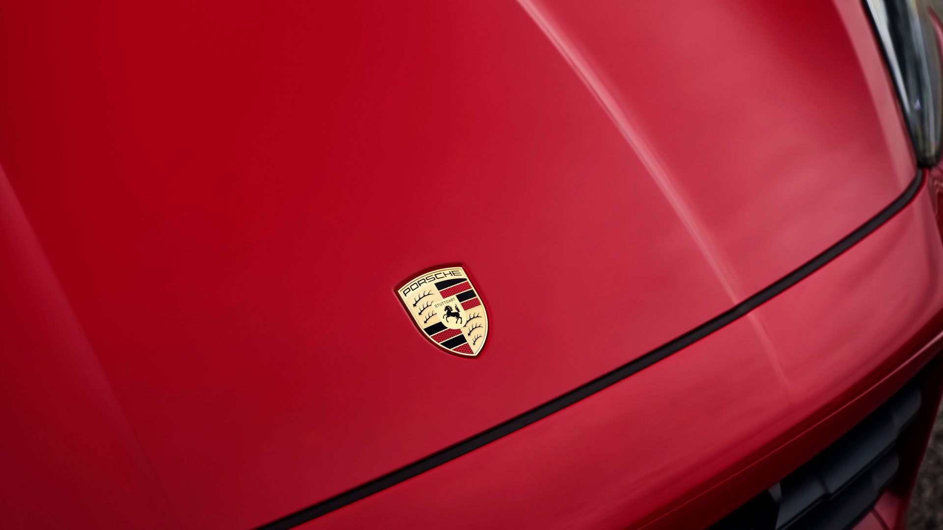Primer plano del emblema de Porsche en el capó de un Cayenne GTS 2024, resaltando su prestigio.