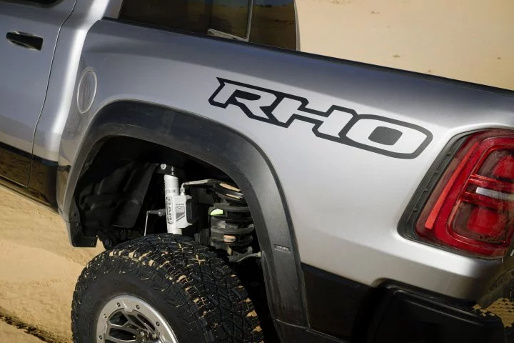 Vista lateral de la insignia RHO en una pickup, neumático todoterreno y suspensión reforzada.