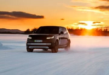 Teaser del Range Rover eléctrico 2024 deslizándose en la nieve, mostrando su frontal y perfil.