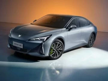 Vista frontal-lateral del sedan eléctrico de lujo, destacando su diseño aerodinámico y moderno. Vista frontal-lateral del sedan eléctrico de lujo, destacando su diseño aerodinámico y moderno.