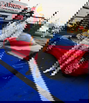 Leyenda del automovilismo posa junto al icónico Honda NSX rojo en el paddock.