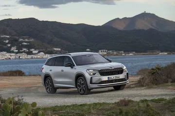 Vista lateral del Škoda Kodiaq 2024 conduciendo por un camino costero.