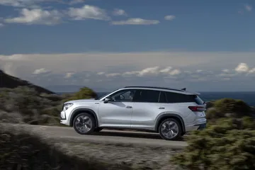 Vista dinámica del Skoda Kodiaq 2024 circulando por carretera con paisaje costero.