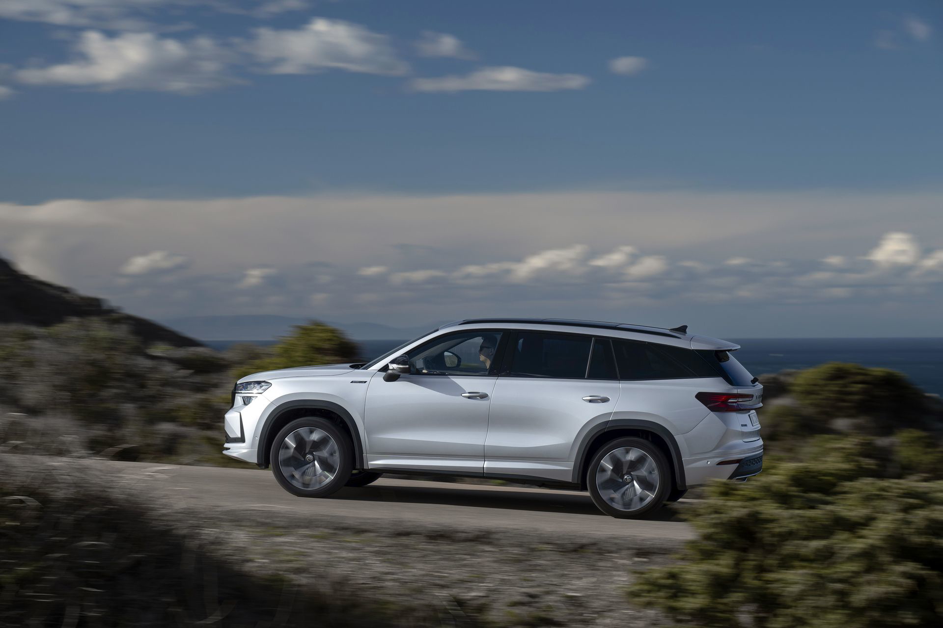 Vista dinámica del Skoda Kodiaq 2024 circulando por carretera con paisaje costero.