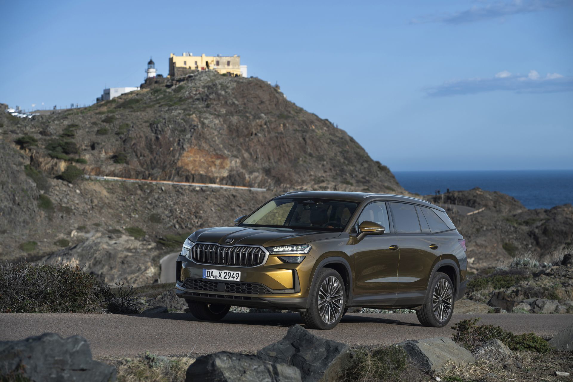 Vista delantera y lateral del Skoda Kodiaq 2024 en carretera con un paisaje montañoso al fondo.