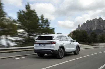Vista dinámica del Skoda Kodiaq 2024 rodando por carretera, ángulo trasero lateral