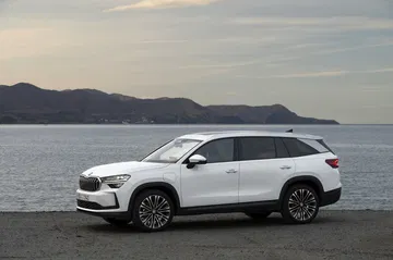 Vista lateral del Skoda Kodiaq 2024 estacionado con paisaje costero de fondo