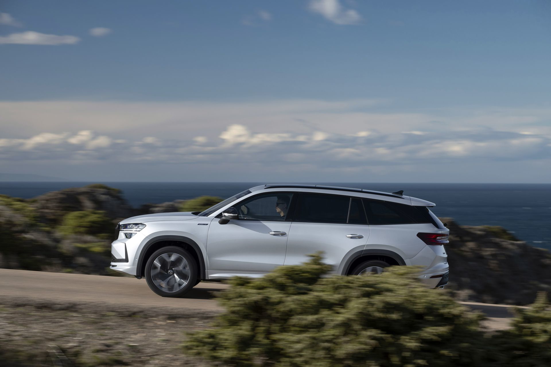 Vista dinámica del Skoda Kodiaq 2024 en carretera con fondo de costa y cielo despejado.