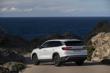 Vista trasera lateral del Skoda Kodiaq 2024, destacando su silueta y diseño en carretera costera.