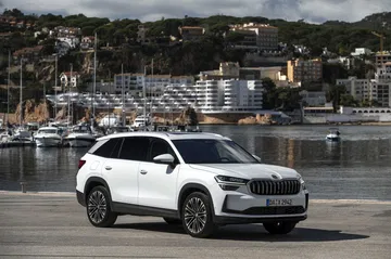 Vista lateral del Skoda Kodiaq 2024 estacionado con paisaje marítimo de fondo.