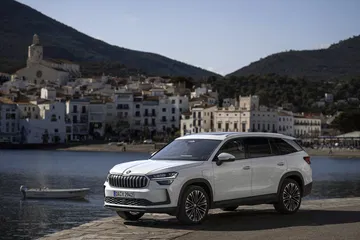 Vista lateral del Škoda Kodiaq 2024 aparcado con un paisaje costero al fondo.