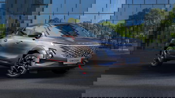 Elegante SUV con líneas dinámicas y acabados premium, reflejando su entorno urbano.