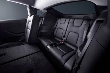 Vista interior trasera del Tesla Model Y 2024, mostrando asientos de cuero negro.