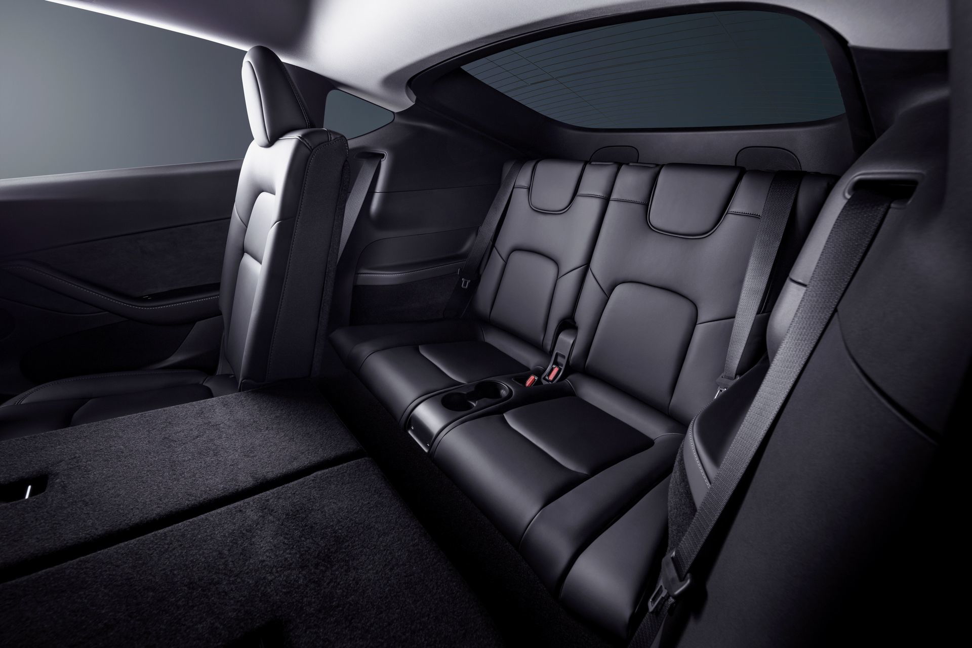 Vista interior trasera del Tesla Model Y 2024, mostrando asientos de cuero negro.