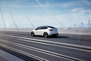 Vista dinámica lateral del Tesla Model Y, destacando su diseño aerodinámico y moderno.