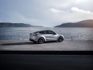 Vista lateral del Tesla Model Y 2024 aparcado frente a un paisaje costero.