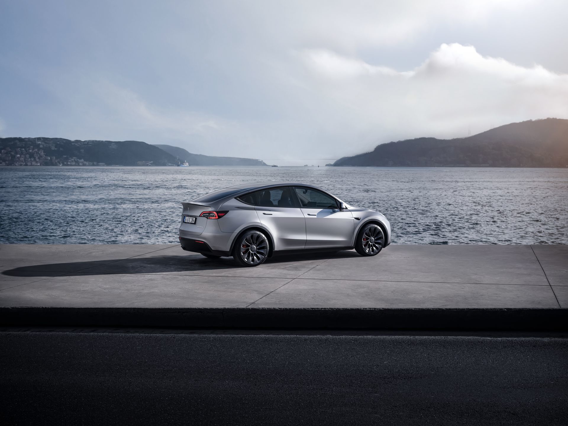 Vista lateral del Tesla Model Y 2024 aparcado frente a un paisaje costero.