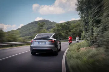 Tesla Model Y capturado en movimiento, destacando su diseño aerodinámico y líneas modernas.
