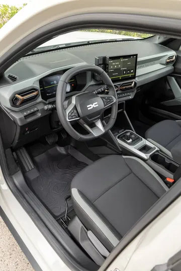 Vista lateral del interior del Dacia Duster, mostrando volante y consola central.