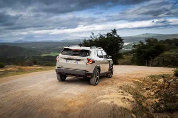 Dacia Duster mostrando su perfil trasero y lateral en un entorno natural.