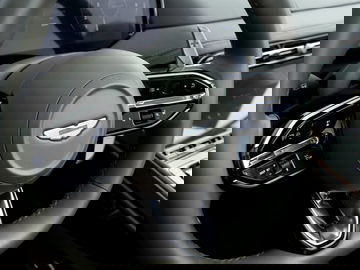 Detalle del volante del Aston Martin con vistas a su emblema sobresaliente y comandos de control.