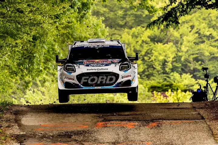 Vista dinámica del Ford Fiesta WRC en acción, suspendido al tomar una curva.
