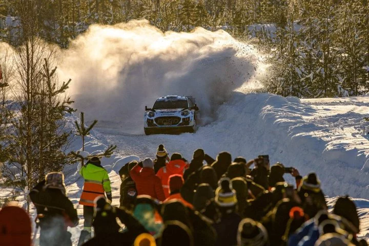 Vehículo de rally desafiando una etapa invernal con espectadores atentos