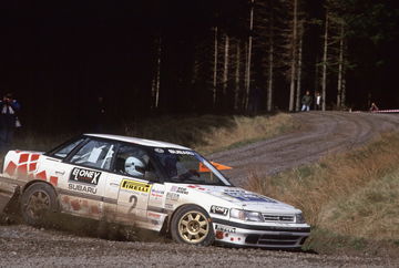 Un Subaru Legacy en plena competición de rally, domina la superficie mixta.