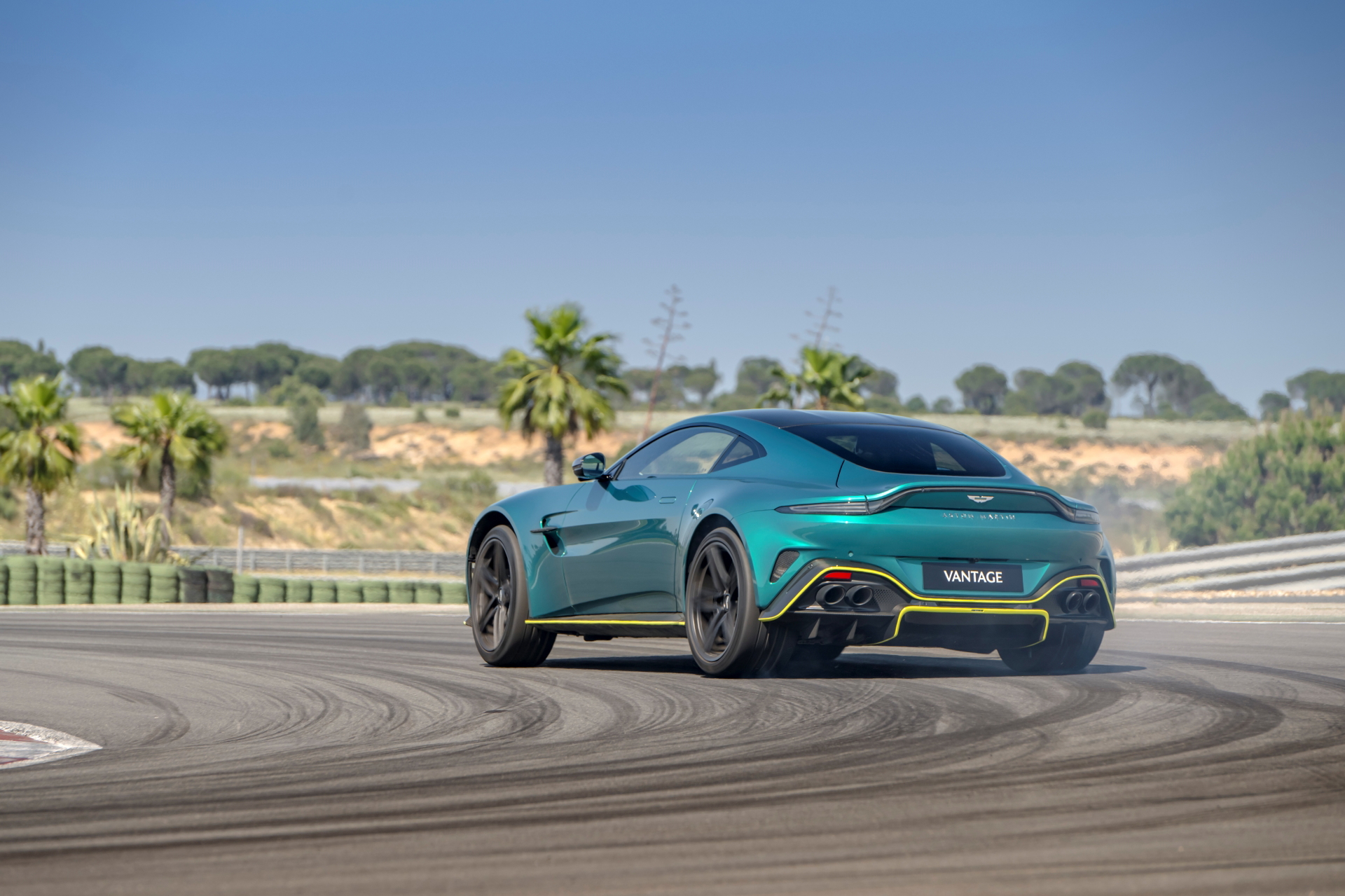 Vista dinámica del Aston Martin Vantage 2024 rodando en circuito, enfatizando su diseño trasero y lateral.