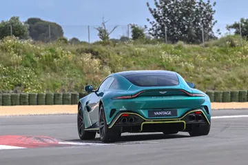 Vista dinámica del Aston Martin Vantage 2024 en pista, destacando su silueta y alerón trasero.