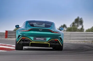 Vista trasera y lateral de un Aston Martin Vantage 2024 en pista, destacando su diseño y escape deportivo.