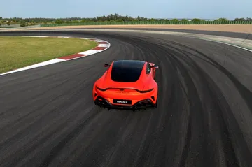 Vista dinámica del Aston Martin Vantage en pista, destacando su diseño trasero y perfil lateral.