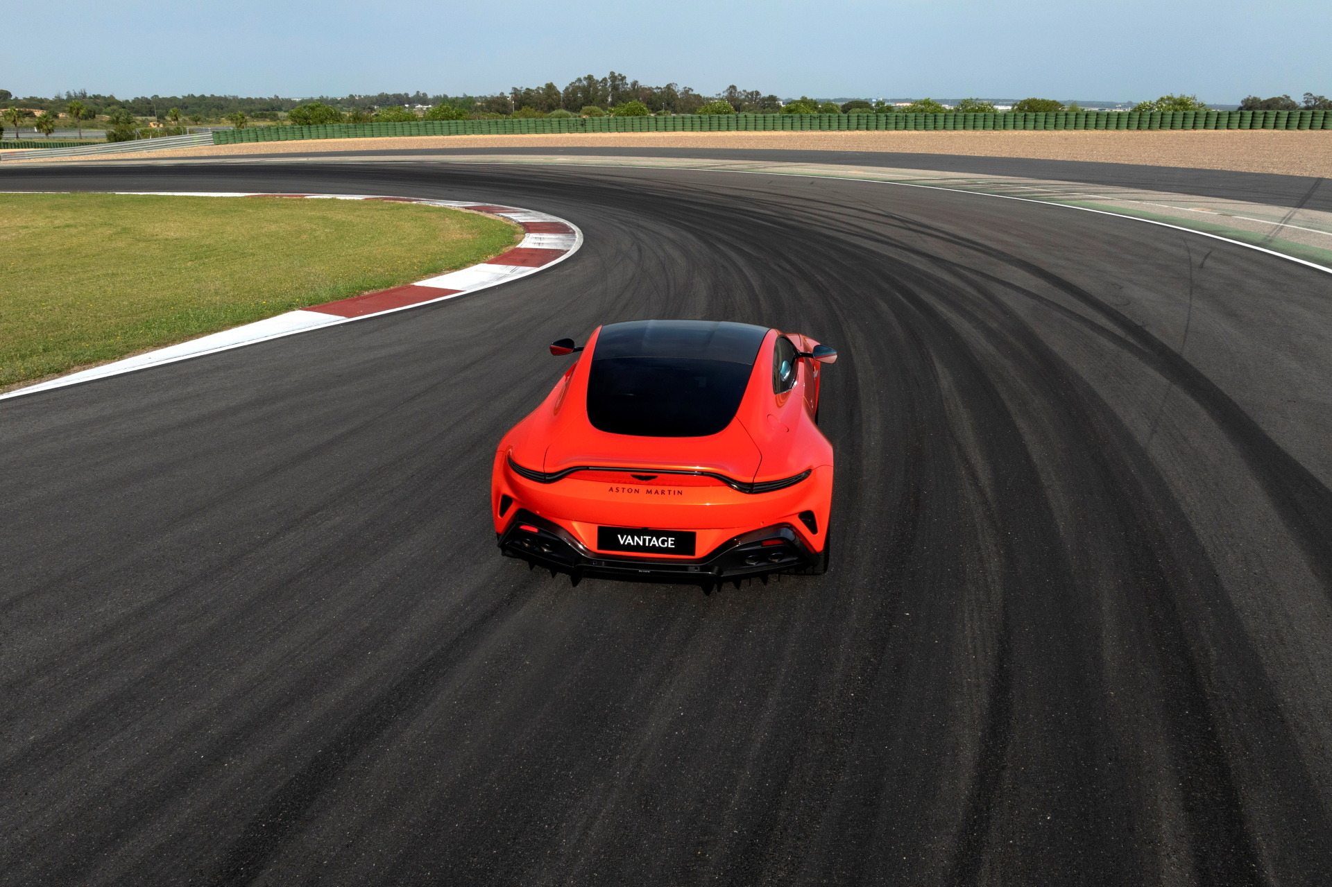 Vista dinámica del Aston Martin Vantage en pista, destacando su diseño trasero y perfil lateral.