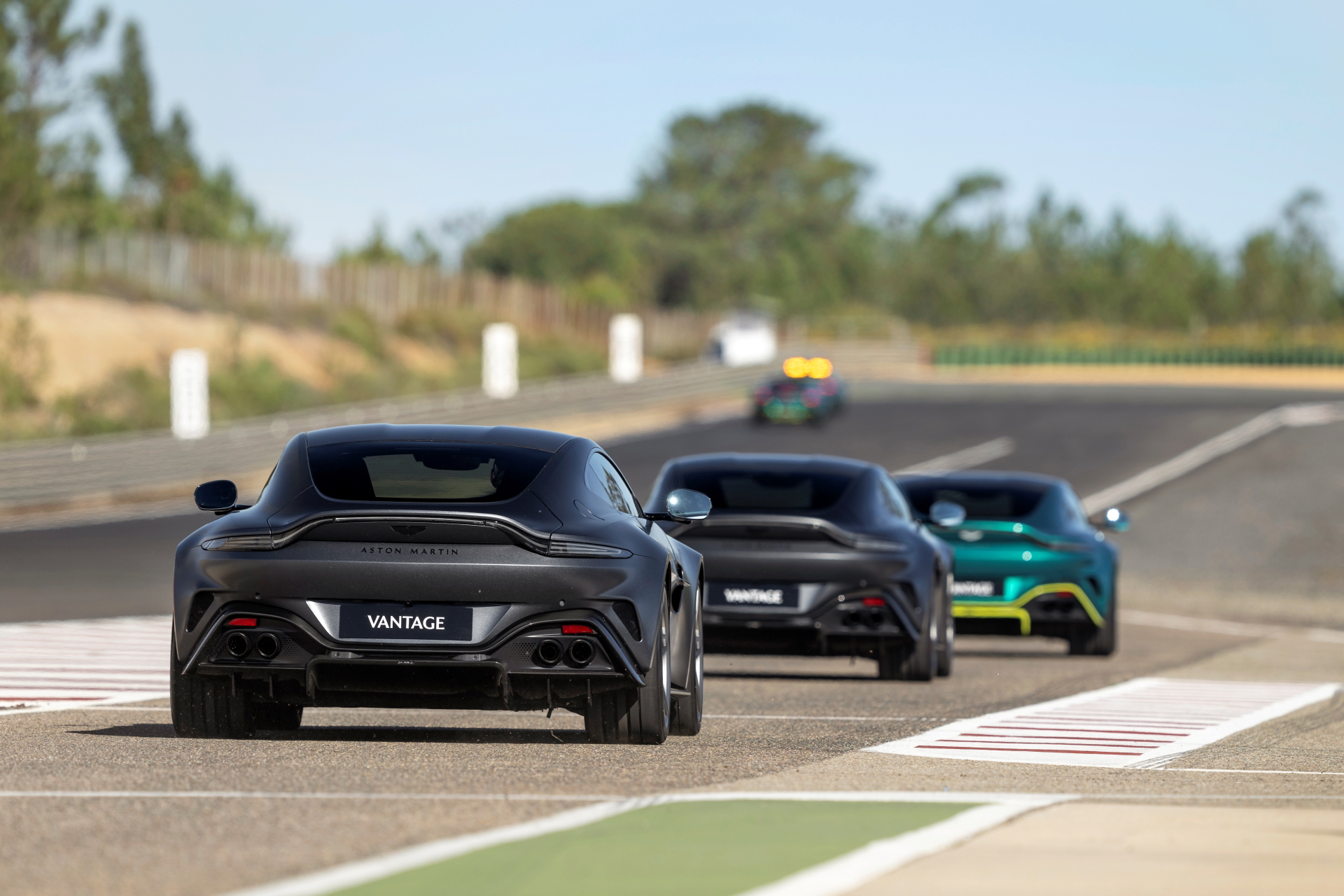Vista trasera de un convoy de Aston Martin Vantage 2024 en pista de pruebas.