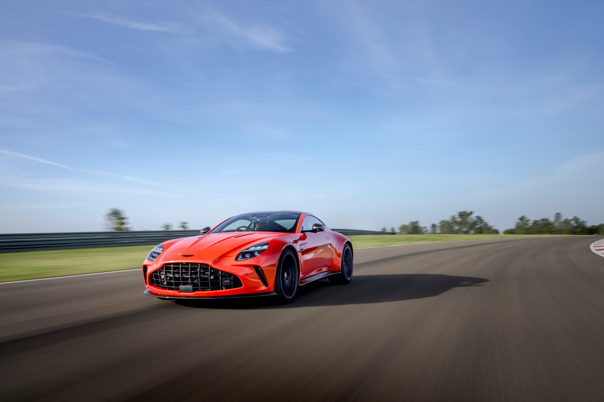 Vista lateral del Aston Martin Vantage 2024 en movimiento, destacando su diseño aerodinámico.