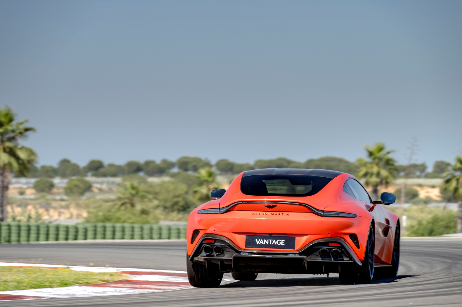 Vista trasera y lateral del Aston Martin Vantage 2024 en pista, mostrando su diseño deportivo y dinámico.