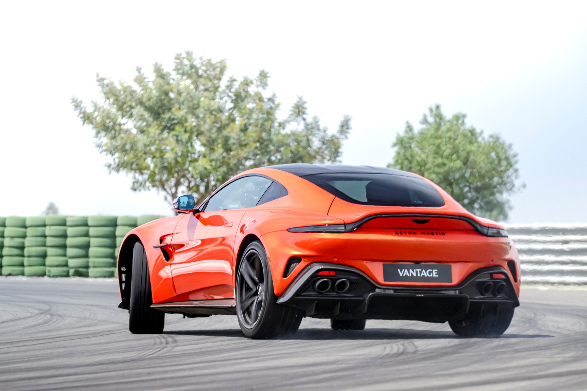 Vista trasera y lateral del Aston Martin Vantage 2024 en color naranja.