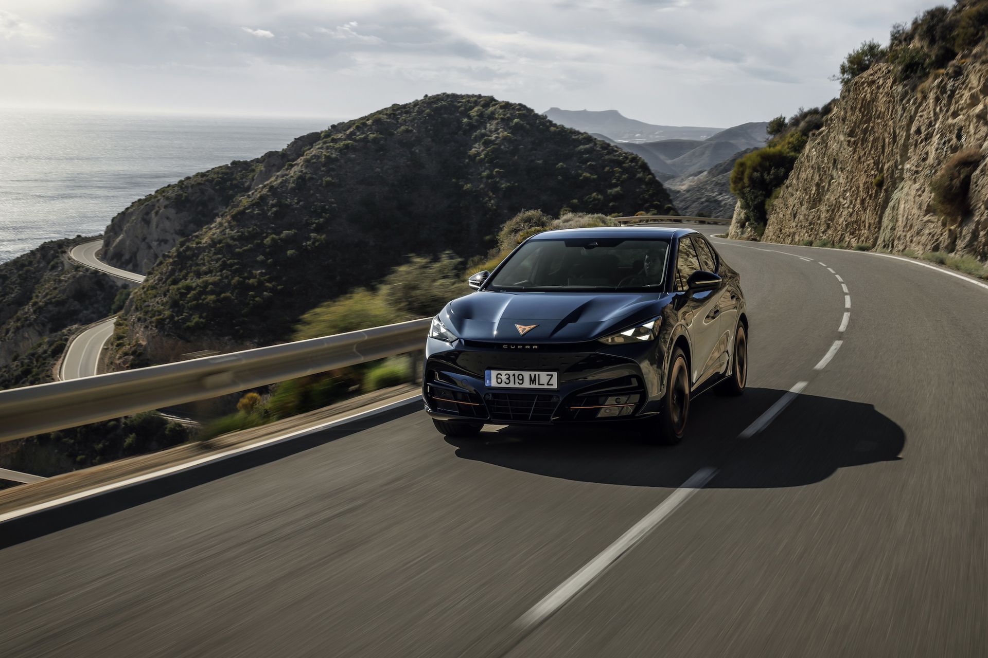 Vista dinámica del CUPRA Tavascan VZ circulando por carretera de montaña