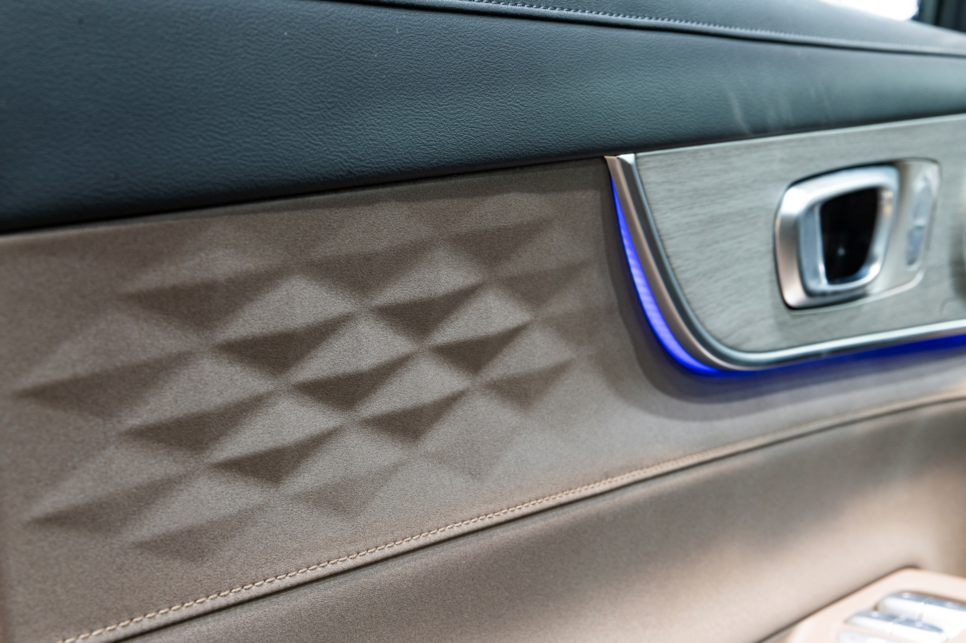 Detalle de acabado de la puerta con pespunteado y emblema estilizado.