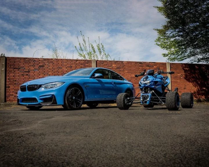 Exhibición de un BMW azul y un quad a juego en una pose desafiante