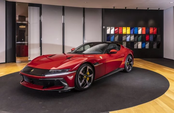 Vista lateral del Ferrari con diseño vanguardista y aerodinámico en una sala de exposición.