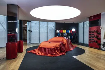 Un Ferrari bajo lona anticipa su majestuosidad, listo para la revelación.