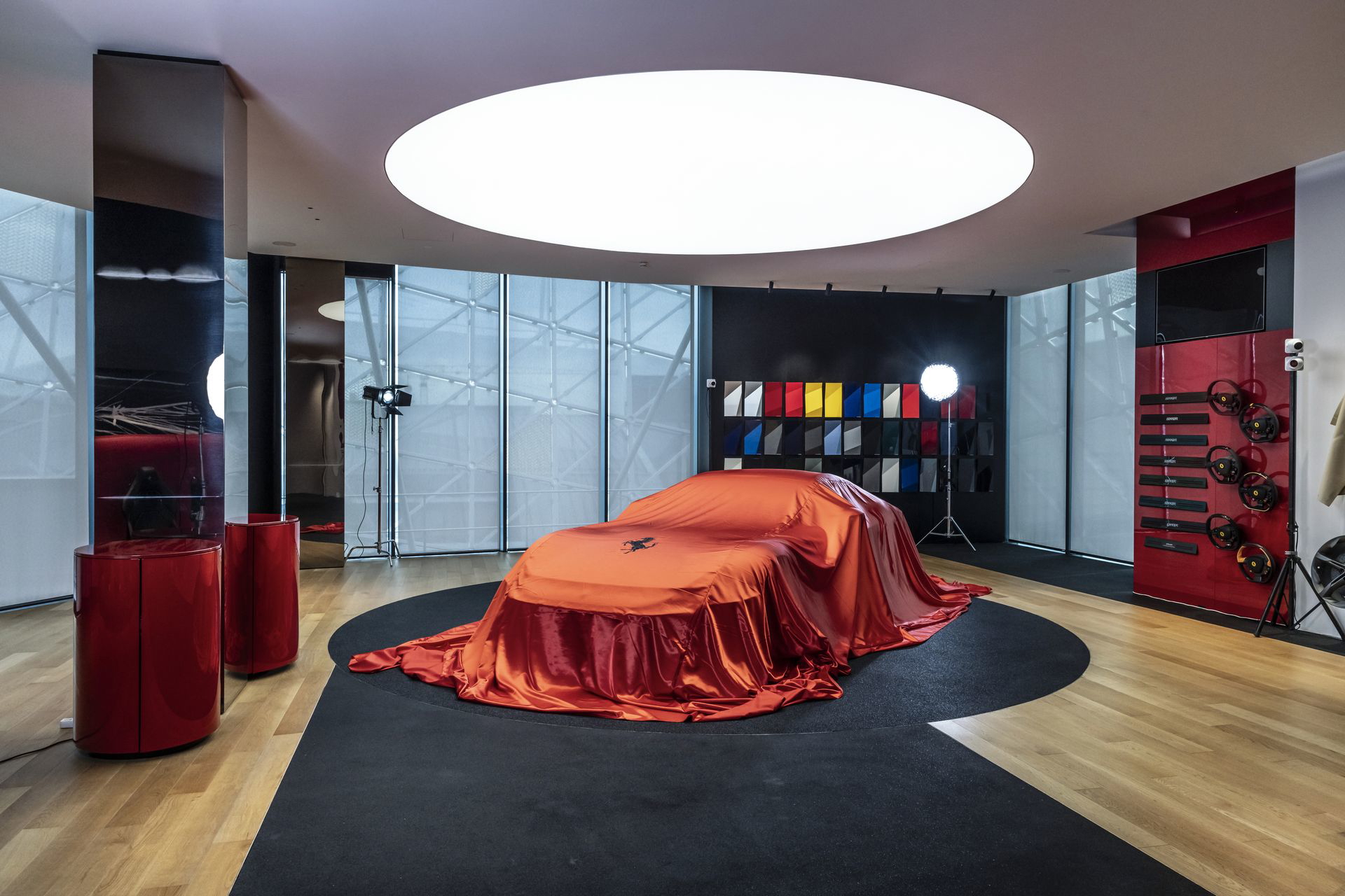 Un Ferrari bajo lona anticipa su majestuosidad, listo para la revelación.