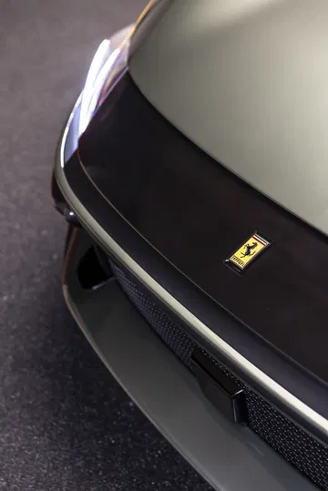 Vista parcial del frontal de un Ferrari, enfocando el emblema.