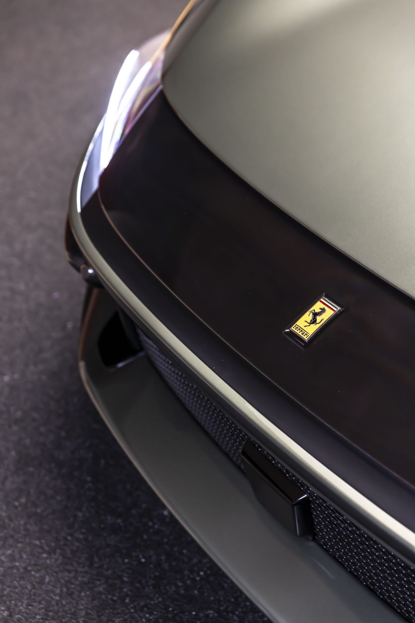 Vista parcial del frontal de un Ferrari, enfocando el emblema.