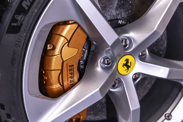 Vista cercana del icónico freno carbono-cerámico de Ferrari con pinza dorada.